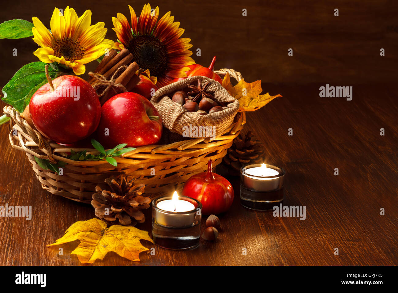 Autunno still life disposizione delle mele,dadi,candele,zucche e girasoli su scuro dello sfondo in legno Foto Stock