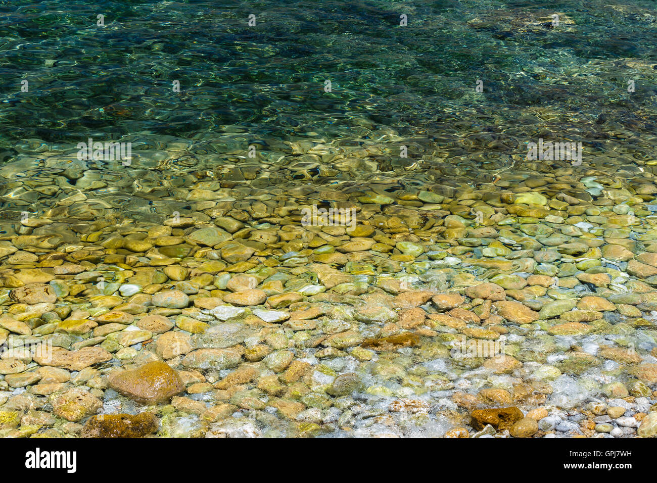 Acqua di mare ed i ciottoli di un verde naturale texture di sfondo, riflettendo al sole, selezionare la messa a fuoco con una buona profondità di campo Foto Stock