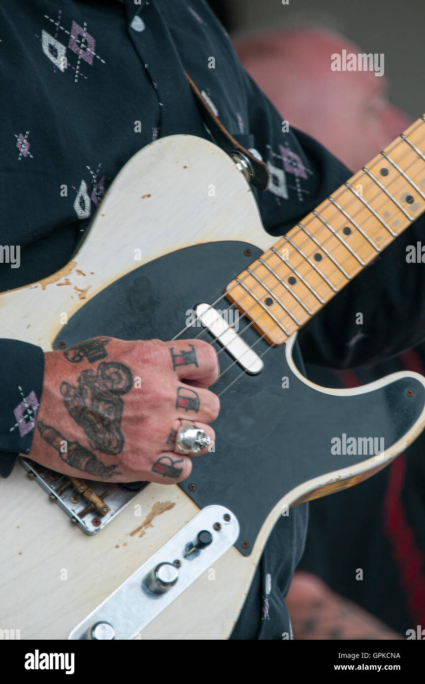 Tatuato mano con la parola RIDE sulle dita a suonare la chitarra su un rock and roll gig in Ace Cafe a Brighton motociclo evento. Foto Stock