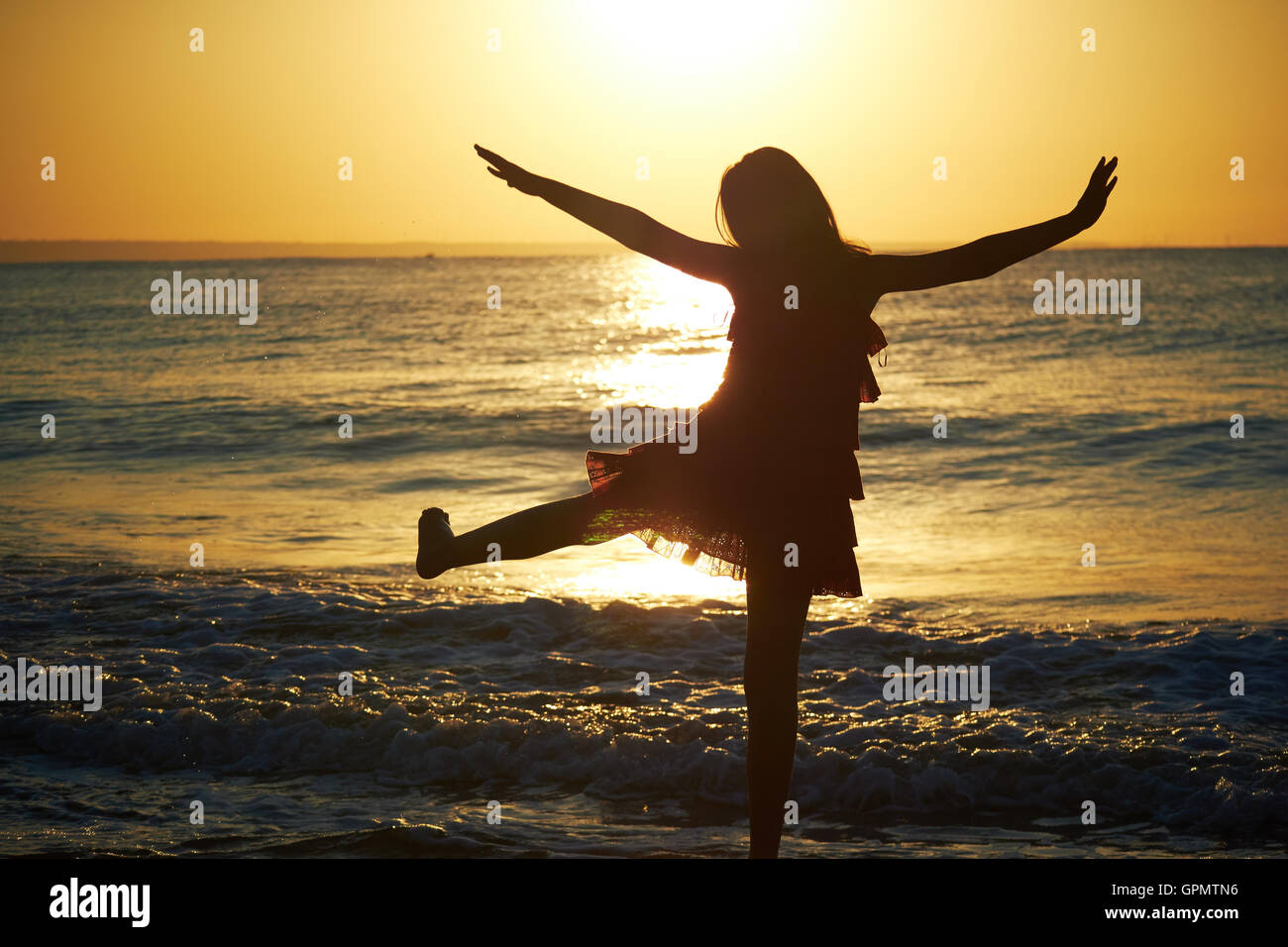 Ragazza giocando sulla spiaggia al tramonto Foto Stock