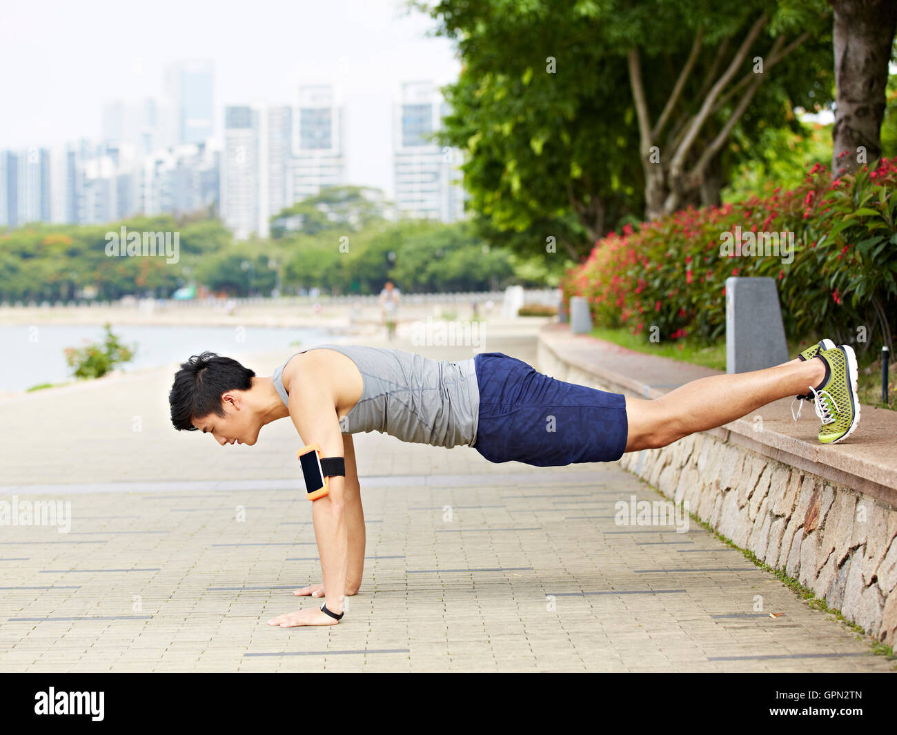 Asian giovane uomo facendo esercizio facendo push-ups in un parco della città Foto Stock