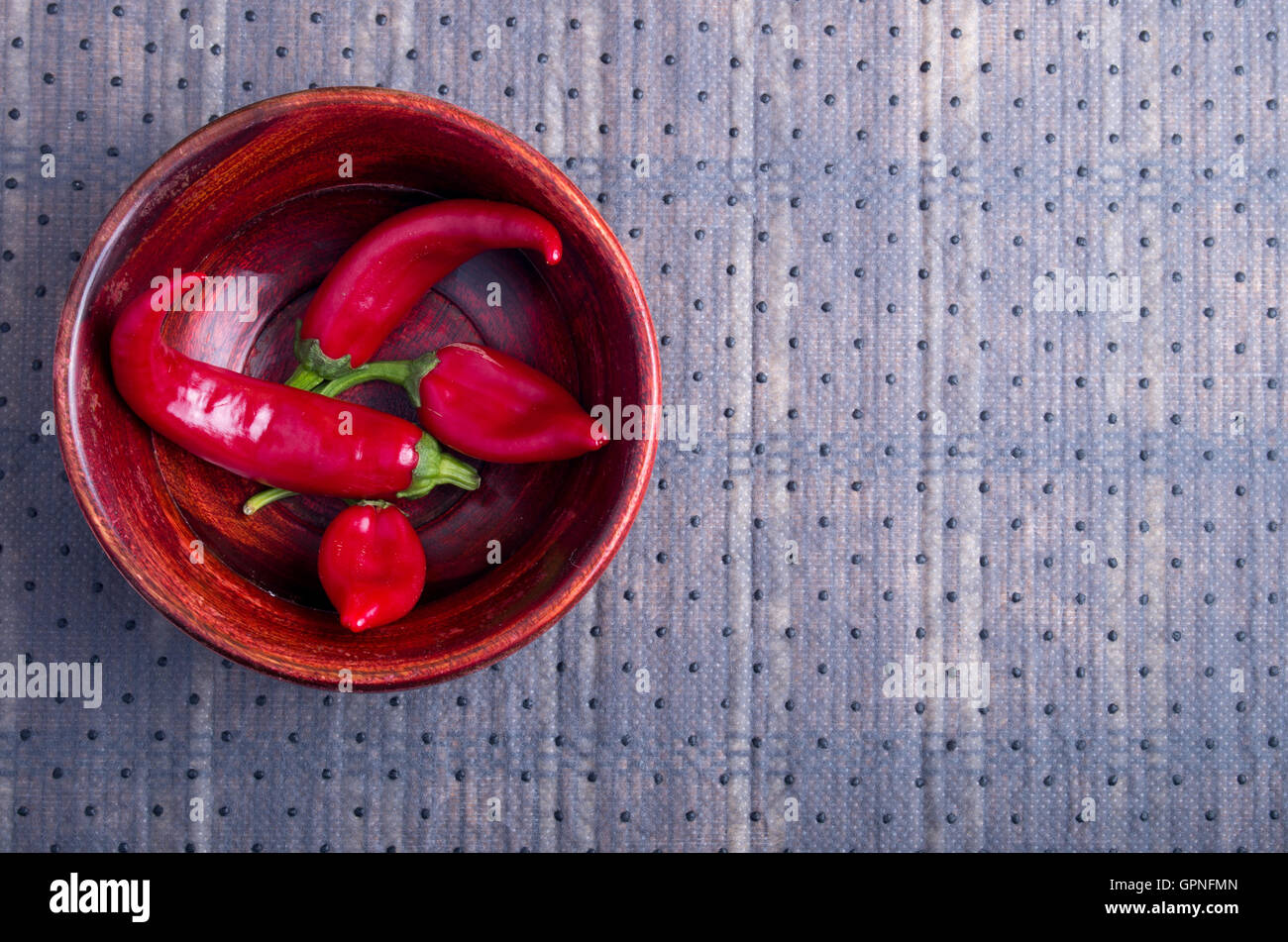 Vista superiore della hot peperoncino rosso in un marrone ciotola di legno su uno sfondo di tessuto Foto Stock