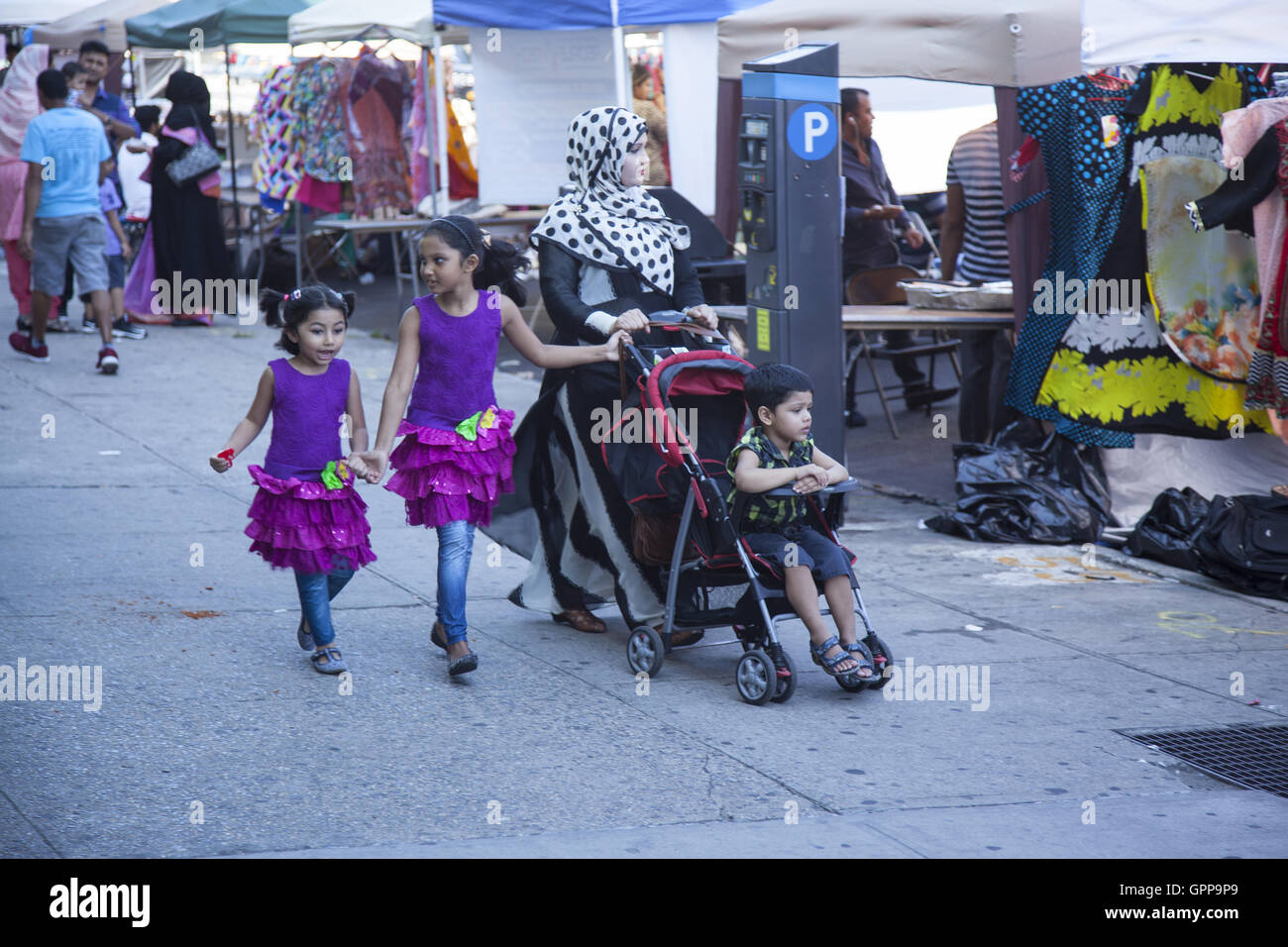 La madre cammina con i suoi figli a una fiera di strada in 'Piccolo Bangladesh' quartiere lungo McDonald Avenue nella sezione di Kensington di Brooklyn, New York. Foto Stock