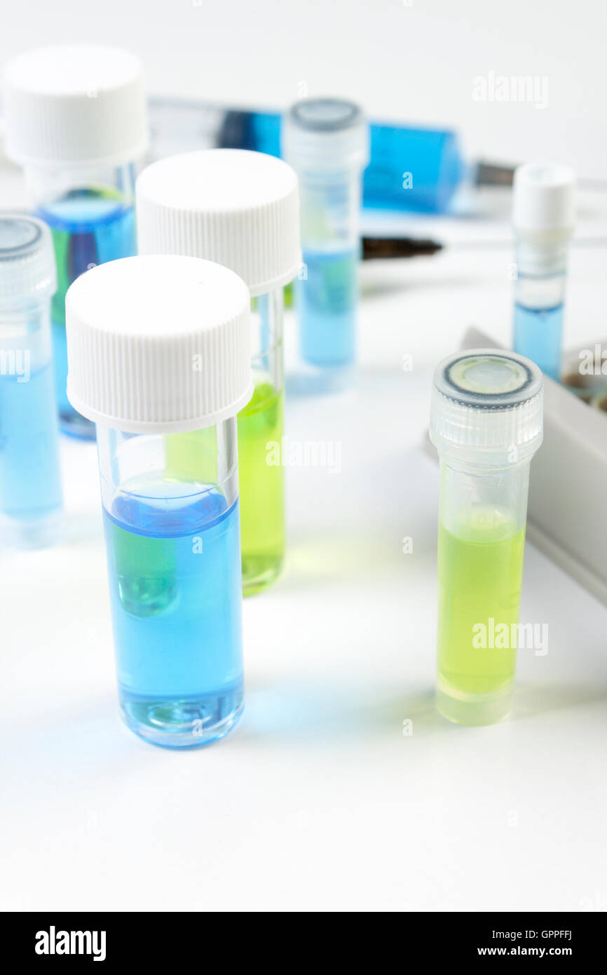 Close up di fiale contenenti il blu e il verde fluidi su un laboratorio di bianco sul banco di lavoro Foto Stock