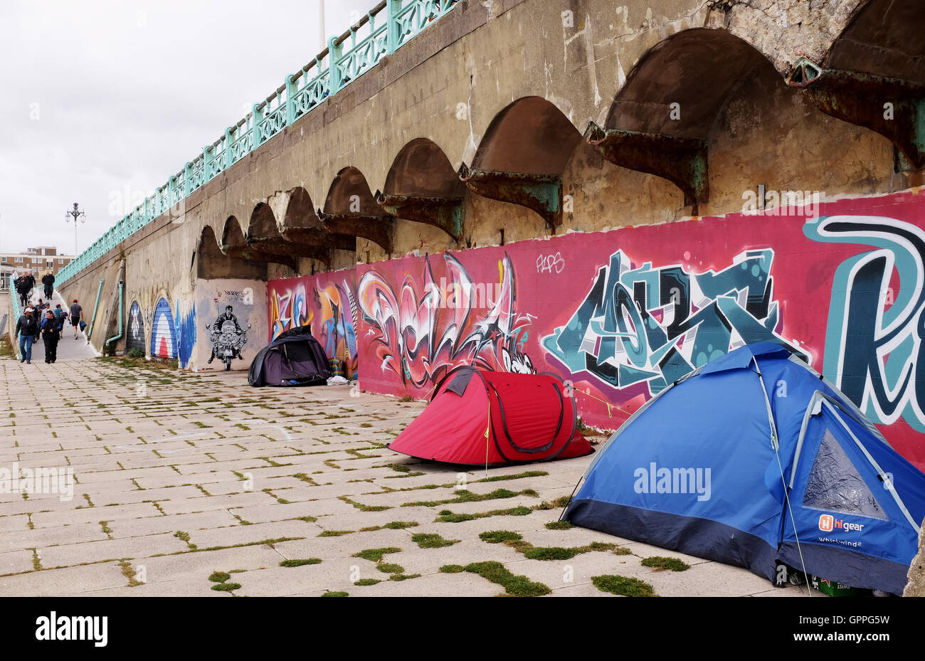 Omaggio arte dei graffiti a un mod su uno scooter per artista Jef Aerosol lungo gli archi sul lungomare di Brighton con senzatetto tende Foto Stock