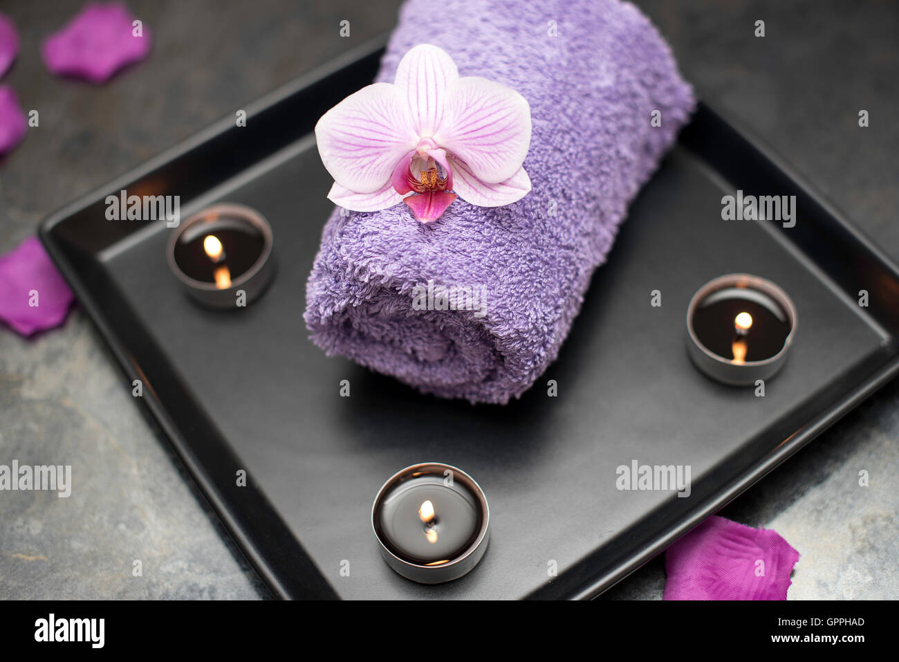 Salone di bellezza decorazione nella sala massaggi, candele, asciugamano e orchidee. Foto Stock