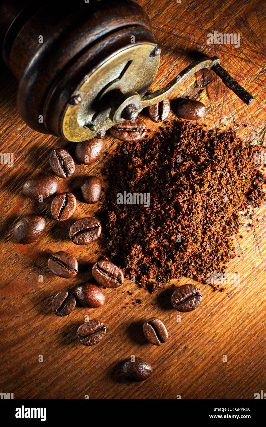 Caffè macinato fresco con la smerigliatrice a mano su sfondo di legno. Foto Stock