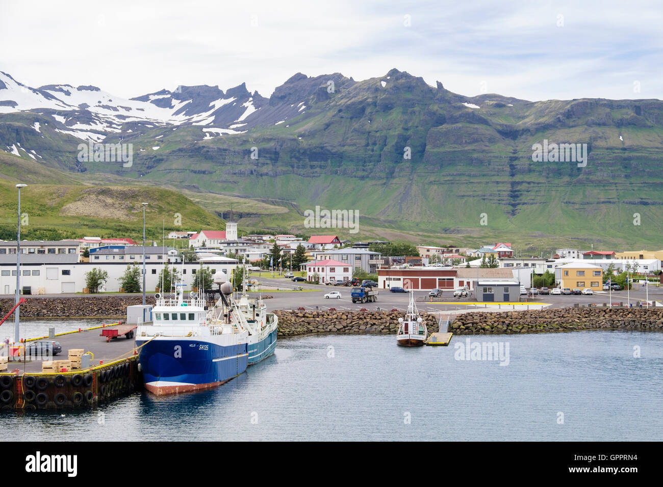 Vista della piccola cittadina islandese al di sotto delle montagne dal porto con ormeggiate barche da pesca. Grundarfjordur Penisola Snaefellsnes in Islanda Foto Stock