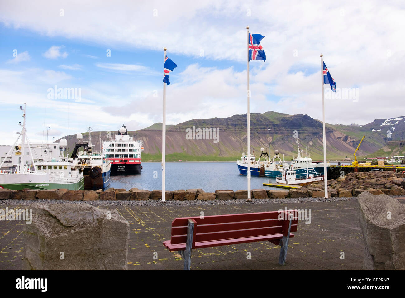 Islandese di bandiere che sventolano sulla banchina con barche da pesca e una nave da crociera ormeggiata in porto. Snaefellsnes Grundarfjordur Islanda Foto Stock