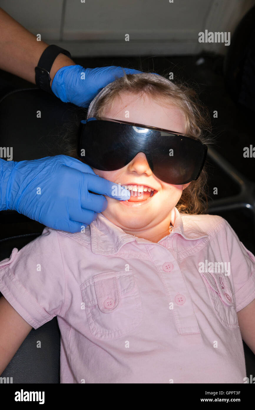 Ragazza 4 anni 4 anno di età bambino indossare occhiali di protezione durante il check up @ dentista per bambini / bambini pratica dentale Foto Stock