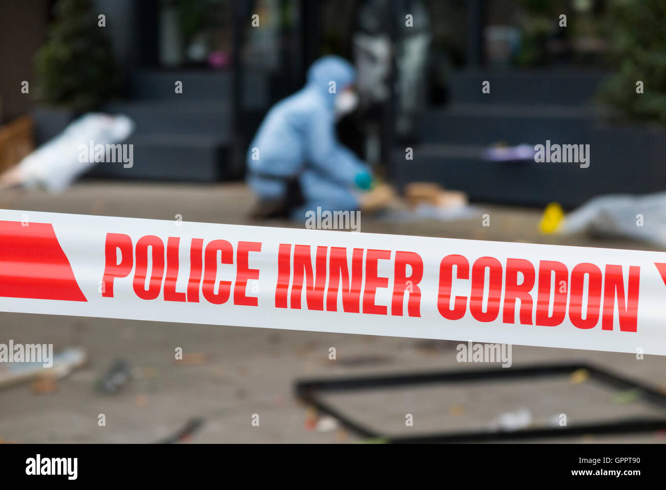 La polizia di cordone interno il nastro di barriera e una scena del crimine officer / ufficiali, & identificazione di prove marcatore numero / marcatori. Regno Unito Foto Stock