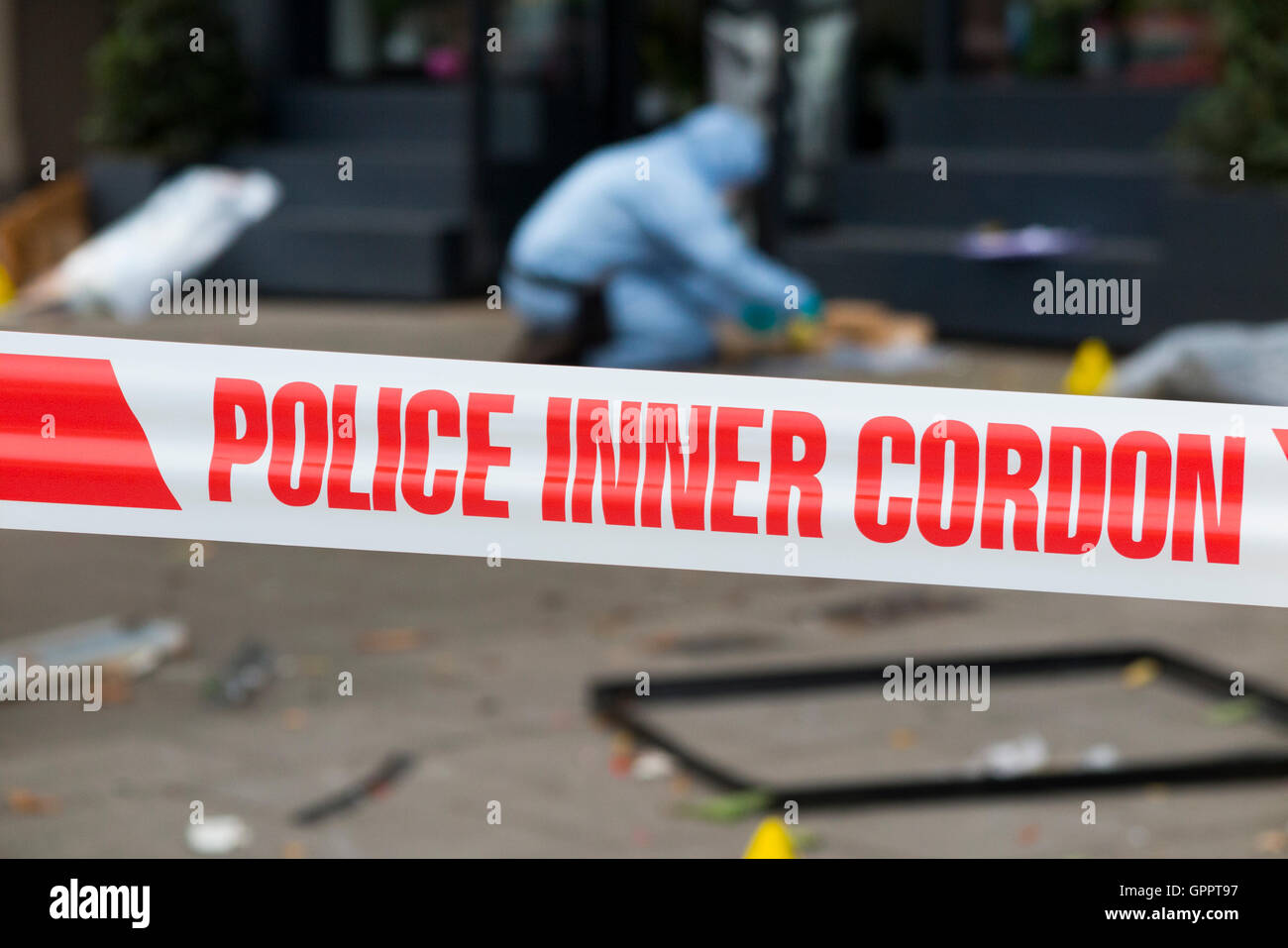 La polizia di cordone interno il nastro di barriera e una scena del crimine officer / ufficiali, & identificazione di prove marcatore numero / marcatori. Regno Unito Foto Stock
