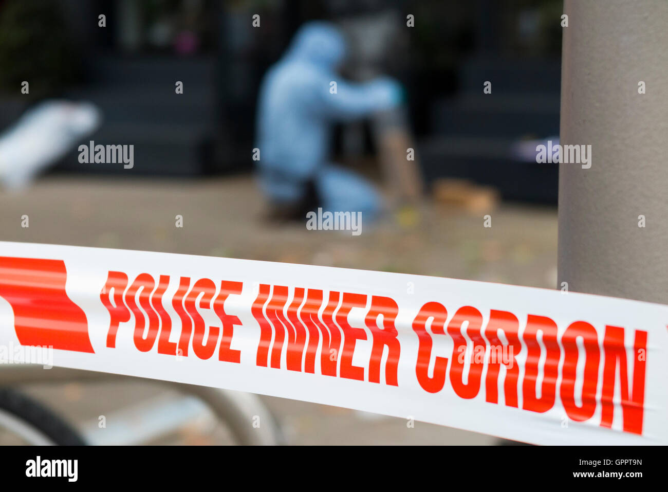 La polizia di cordone interno il nastro di barriera e una scena del crimine officer / ufficiali, & identificazione di prove marcatore numero / marcatori. Regno Unito Foto Stock