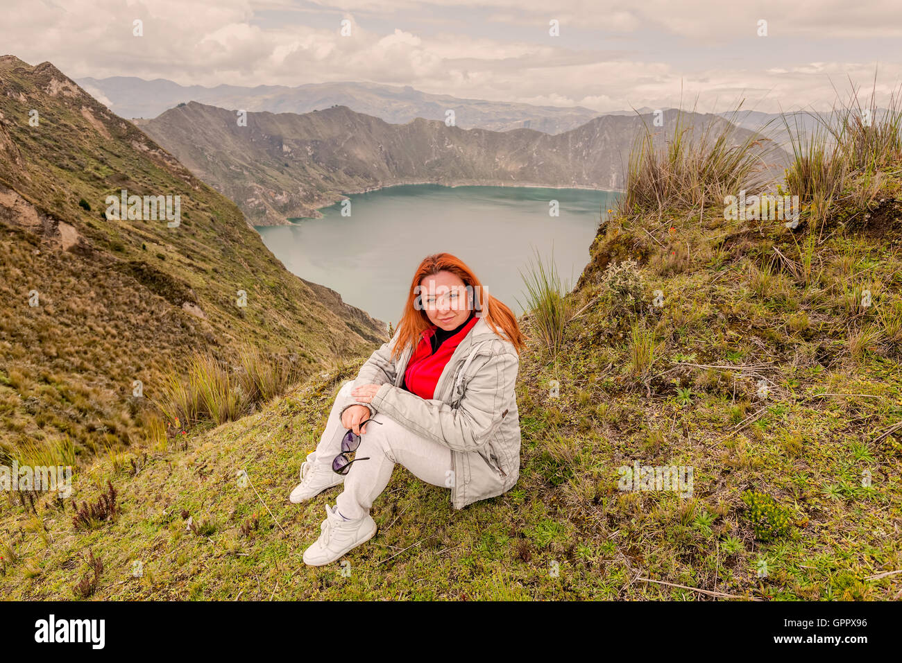 Sorridente bionda Gioventù donna in piedi vicino al cratere del Lago di Quilotoa, Ecuador, Sud America Foto Stock
