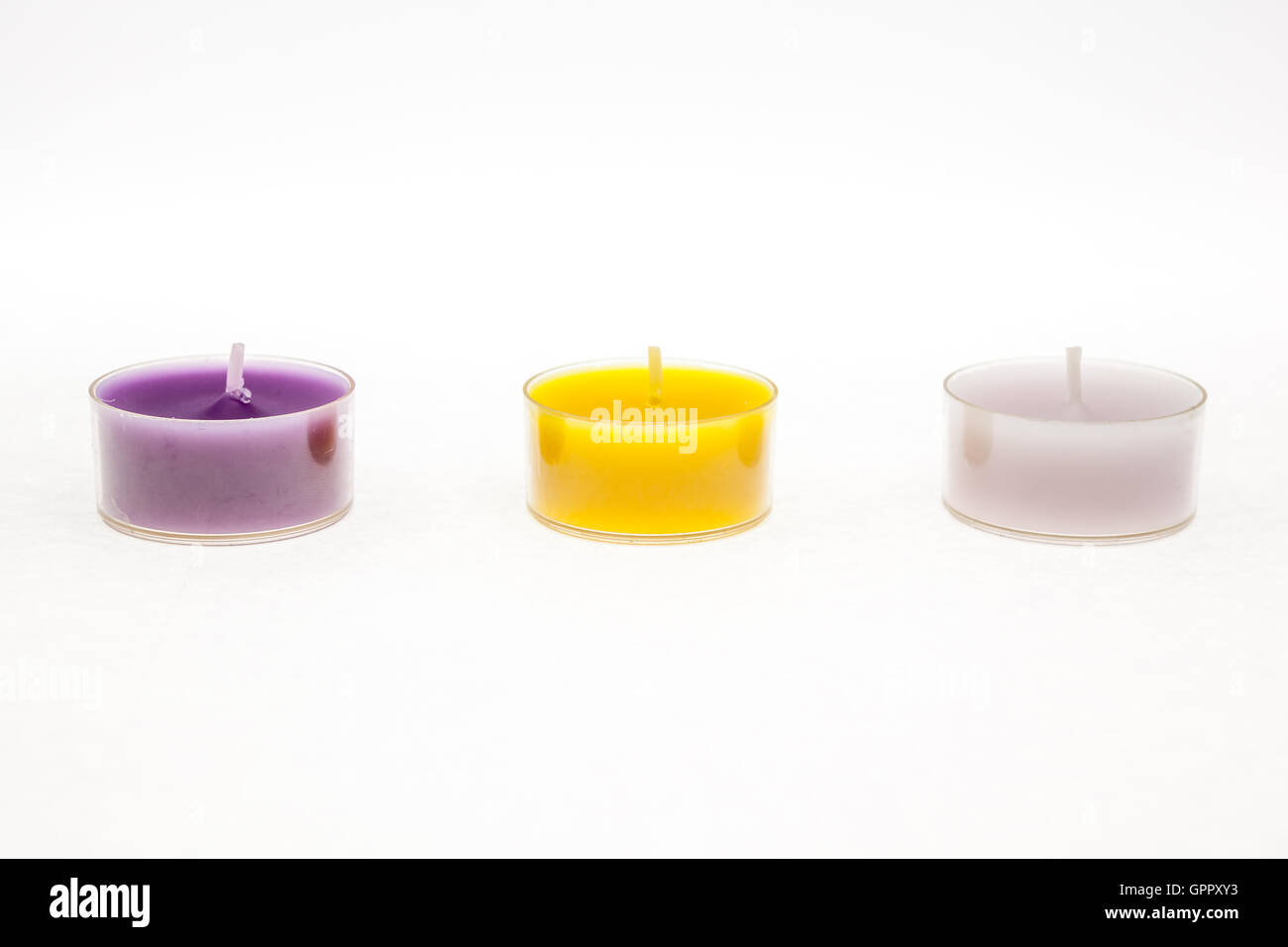 Diversi colori di tè accendono le candele con sfondo bianco Foto Stock