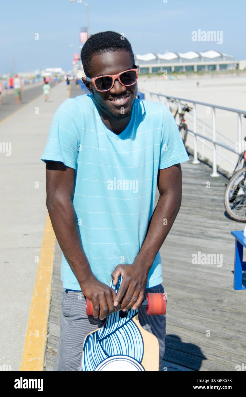 Giovane americano africano uomo con il suo skateboard Foto Stock