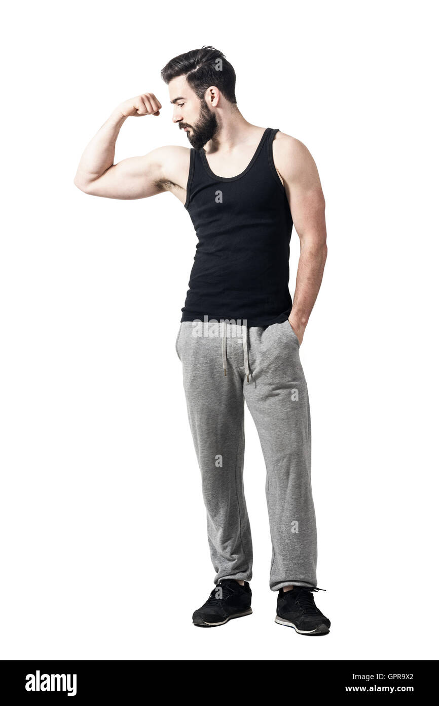 Atleta nel serbatoio nero superiore braccio di flessione bicipite guardando i muscoli. Tonica dissaturato piena lunghezza corpo ritratto isolato su bianco Foto Stock Atleta nel serbatoio nero superiore braccio di flessione bicipite guardando i muscoli. Tonica dissaturato piena lunghezza corpo ritratto isolato su bianco Foto Stock