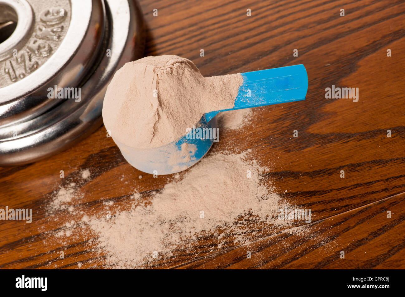 La proteina del siero di latte in polvere in misurino e un manubrio su  sfondo di legno Foto stock - Alamy