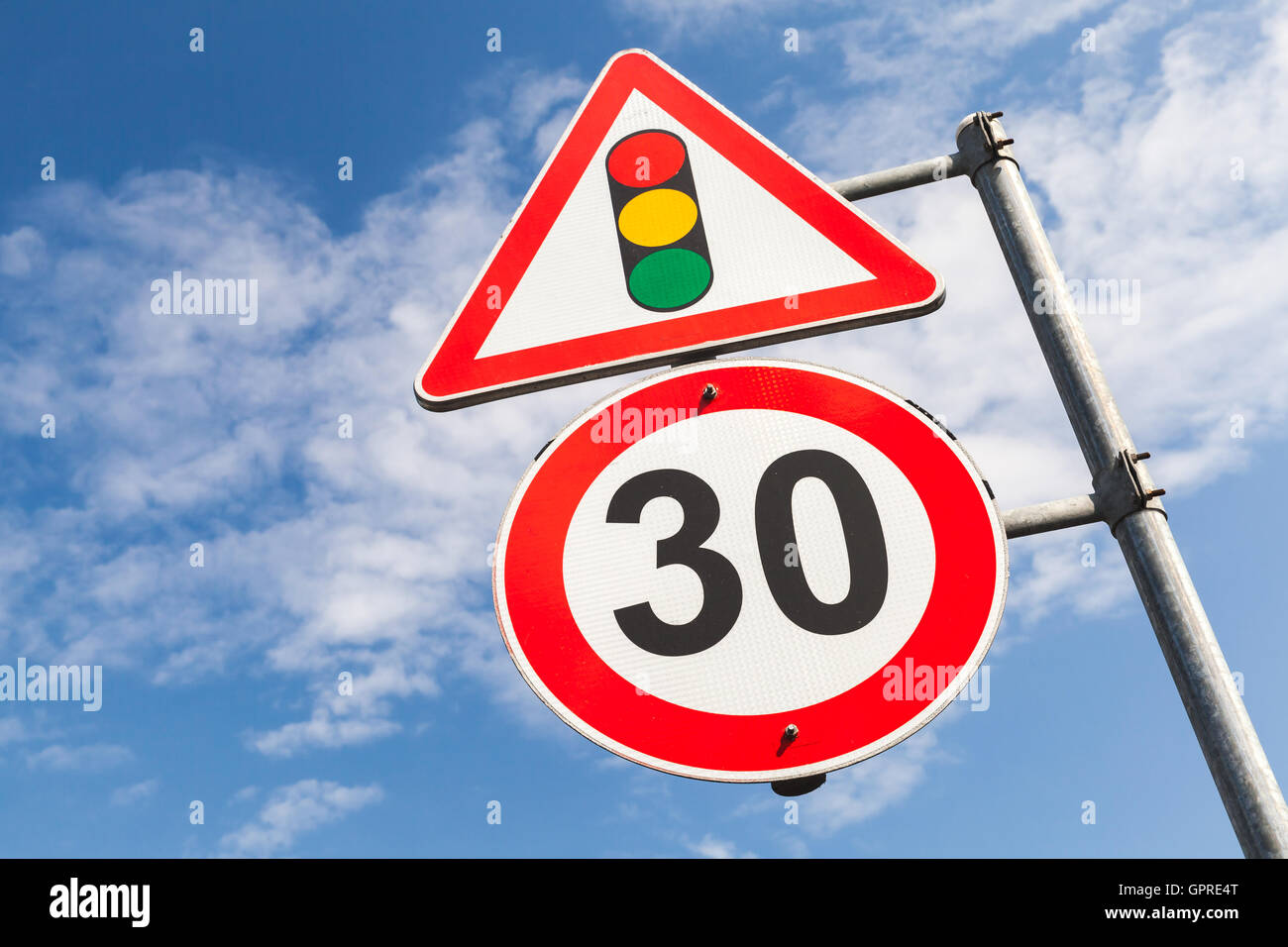 Il semaforo e limite di velocità a 30 km all'ora montato sul montante metallico. Segnaletica stradale oltre il cielo blu sullo sfondo Foto Stock