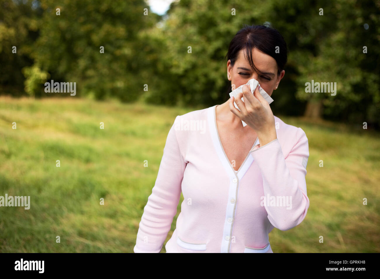 Giovane donna che soffre di un freddo soffia il naso Foto Stock