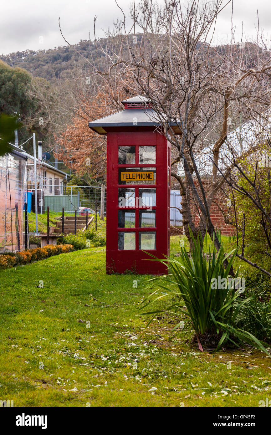 Uno stile vecchio telefono rosso stand in un paese erbosa lane Foto Stock