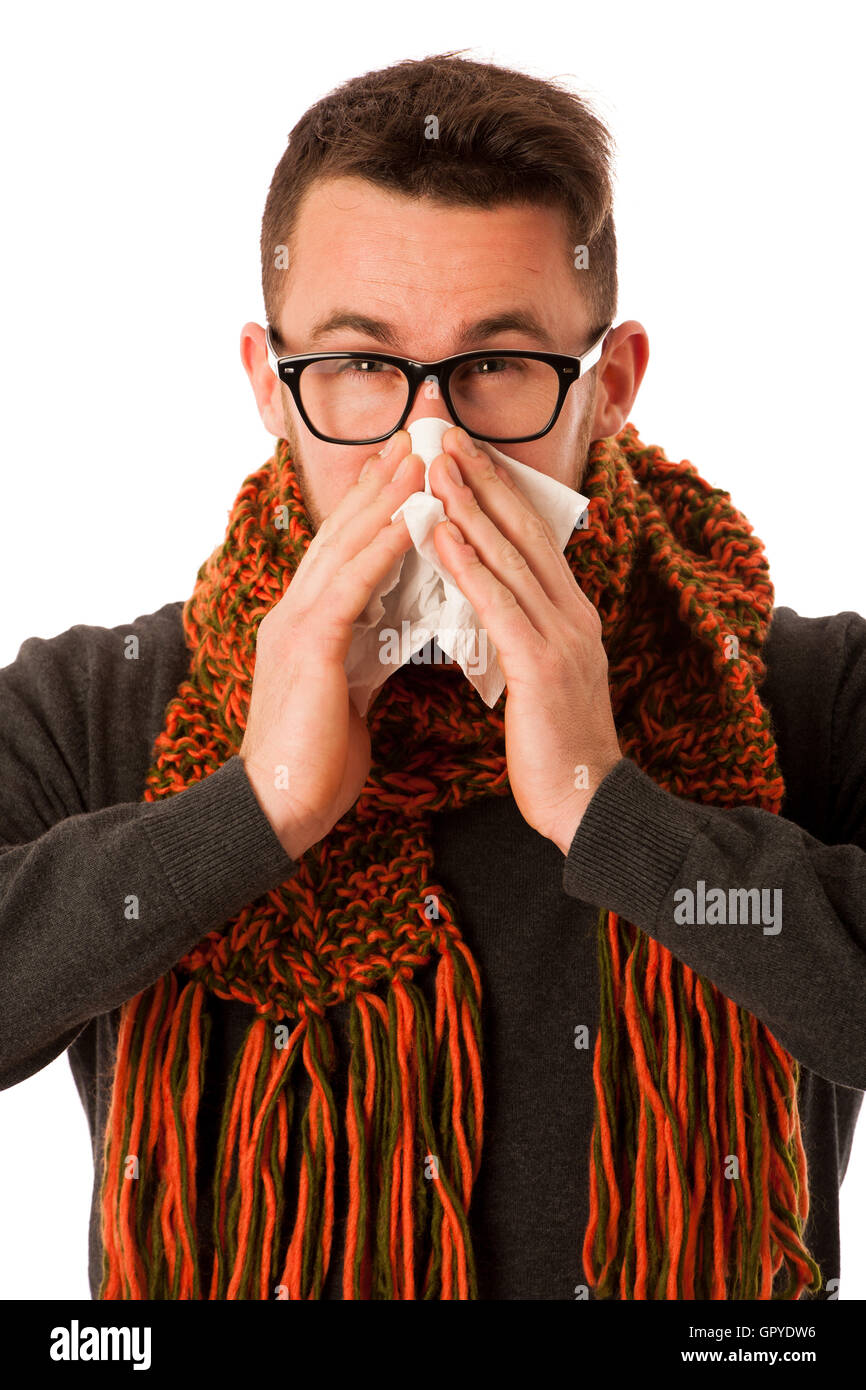 Uomo con influenza e febbre avvolto in una sciarpa starnuti nel fazzoletto isolato su bianco. Foto Stock