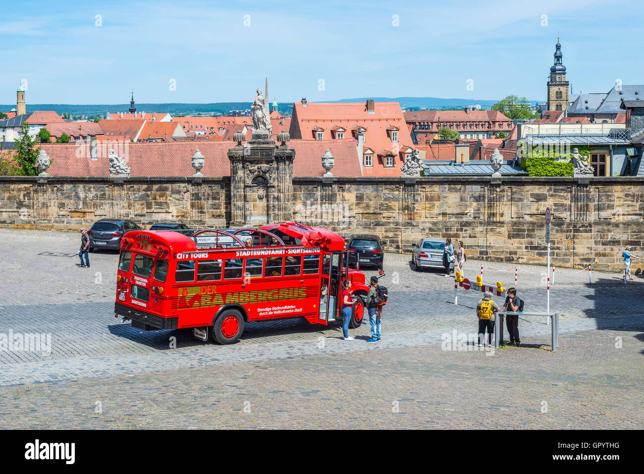 Local bus panoramico e turisti vicino a parete con sculture nella Domplatz di Bamberg, Germania Foto Stock