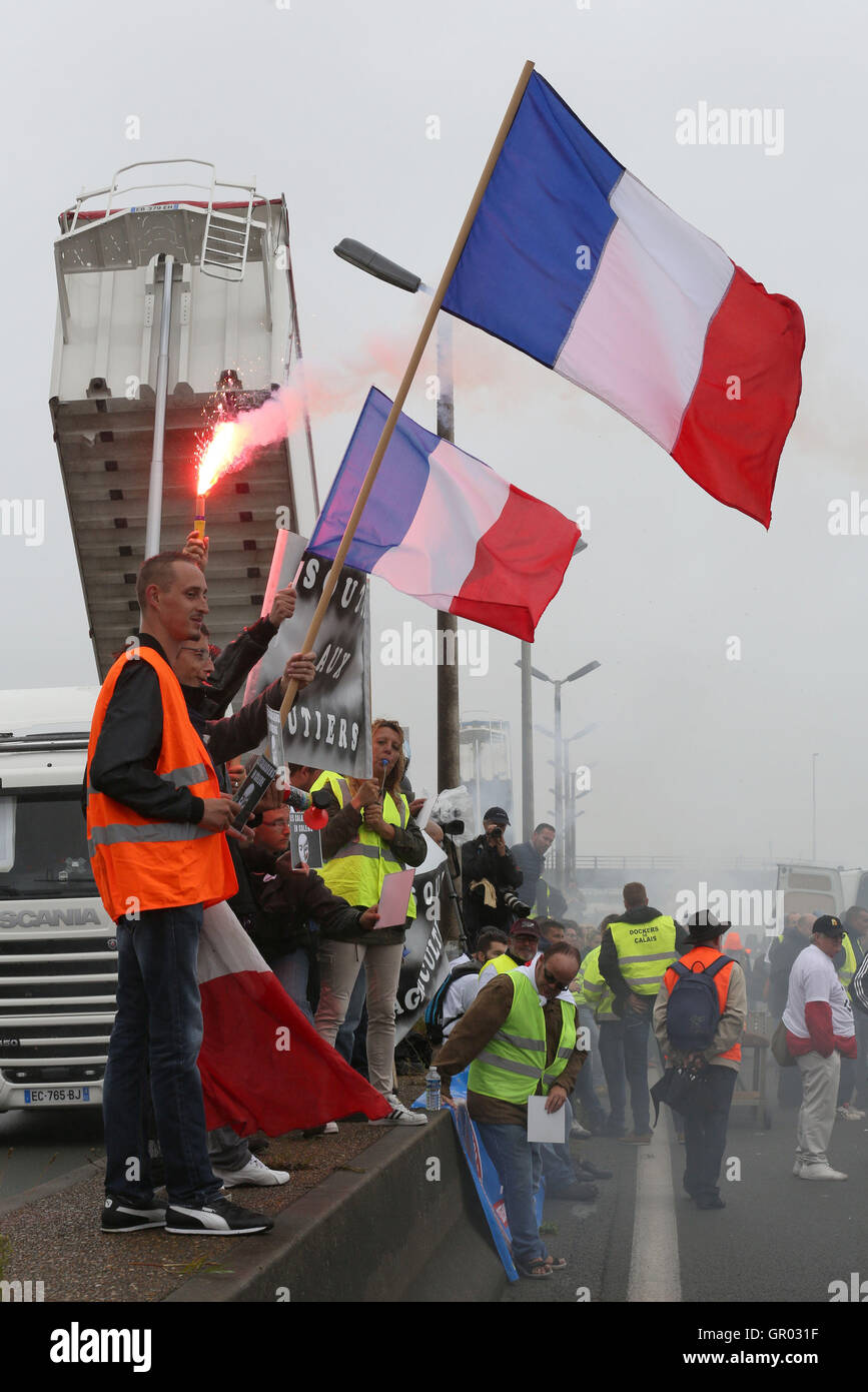 La gente sventolare la bandiera francese come altri marzo sull'autostrada A16 a sostegno di un blocco intorno al porto di Calais in Francia come parte di una campagna per la giungla campo migrante per essere demolita. Foto Stock