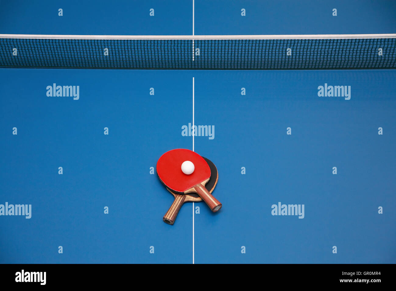 Le racchette per il blu tavolo da ping pong del rosso e del nero e del colore di una sfera su un ping pong, vista da sopra Foto Stock