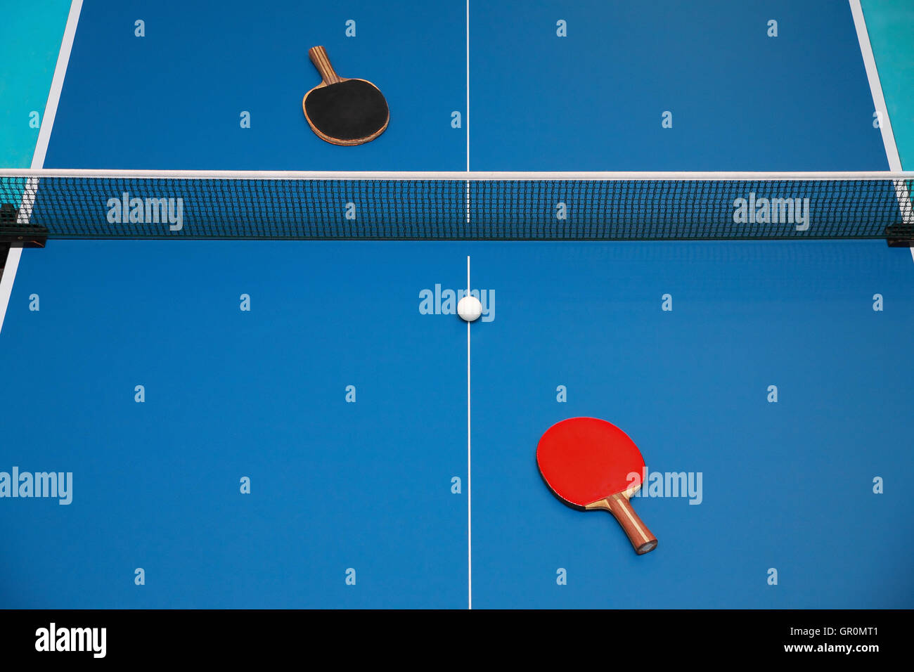 Le racchette per il blu tavolo da ping pong del rosso e del nero e del colore di una sfera su un ping pong, vista da sopra Foto Stock