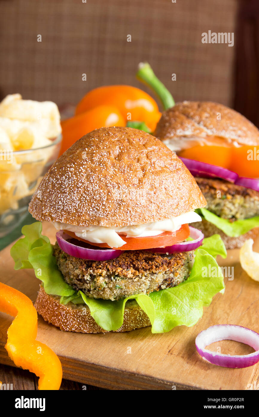 Vegetariano burger di lenticchie con verdure sul tagliere di legno Foto Stock
