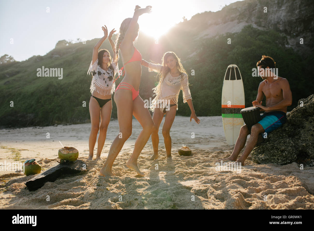 Un gruppo di giovani amici festa sulla spiaggia e balli. I giovani divertirsi presso il beach party, donne che danzano e l uomo la riproduzione Foto Stock