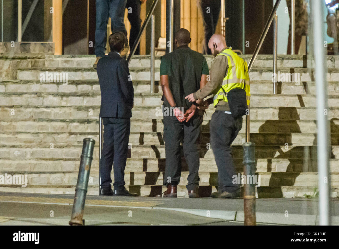 West Bay, Dorset, Regno Unito - 6 Settembre 2016 - David Tennant e Sir Henry Lenny filmare scene di arresto sui gradini della stazione di polizia di notte per la serie 3 di ITV serie hit Broadchurch. Ed Burnett, il personaggio interpretato da Sir Henry Lenny è visto per essere presi in custodia in manette da di Alec Hardy svolto da David Tennant, dopo aver aggredito uno dei mostra caratteri Jim Atwood. Immagine: Graham Hunt/Alamy Live News Foto Stock