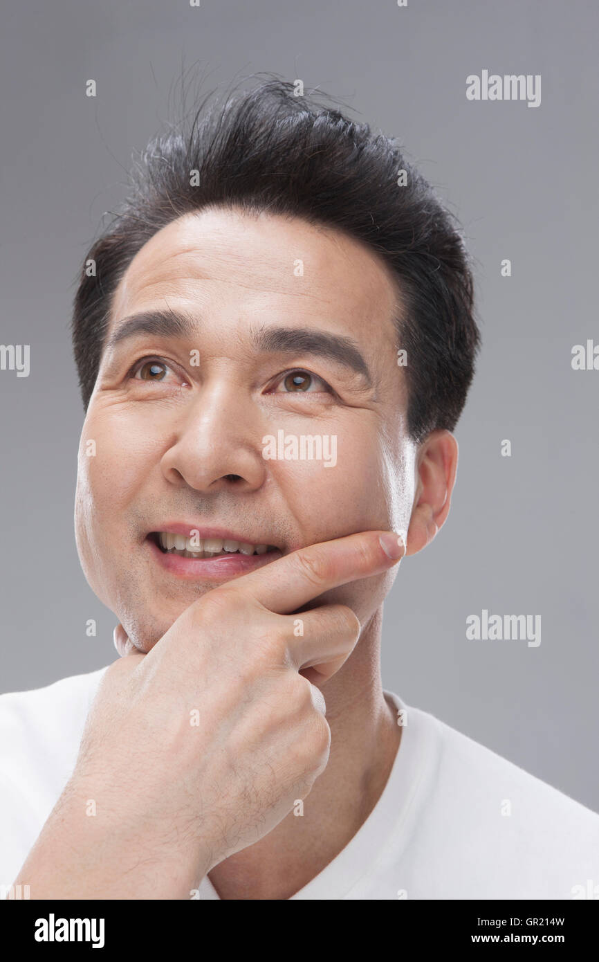 Uomo di mezza età di toccare la faccia Foto Stock