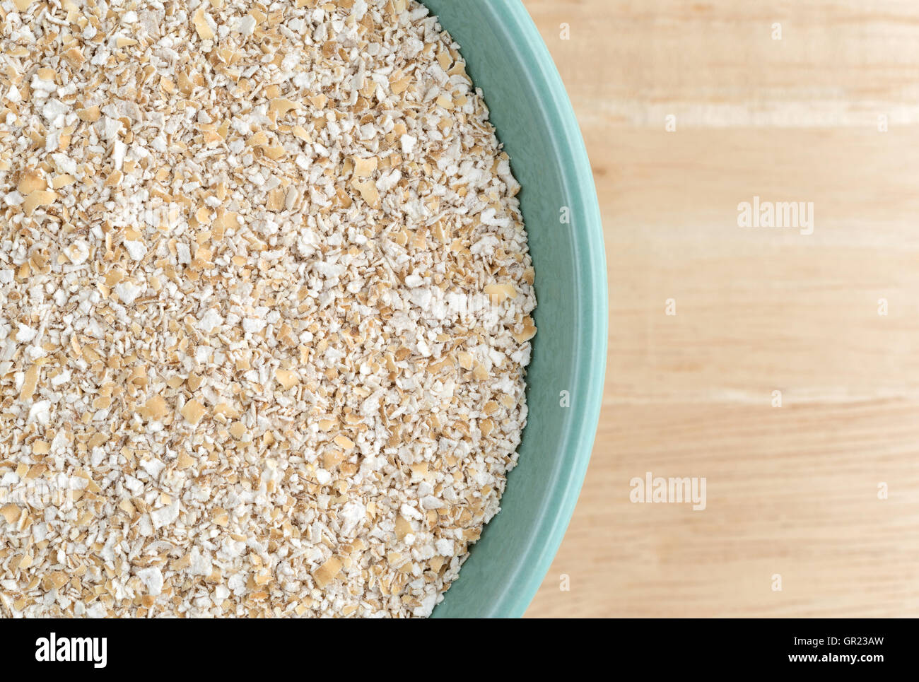 Top Chiudi vista secca di crusca di avena cereale a caldo in un recipiente verde sulla cima di un tavolo di legno. Foto Stock