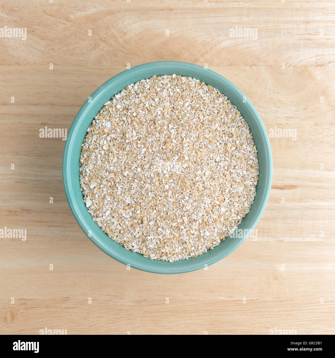 Vista in pianta secca di crusca di avena cereale a caldo in un recipiente verde sulla cima di un tavolo di legno. Foto Stock