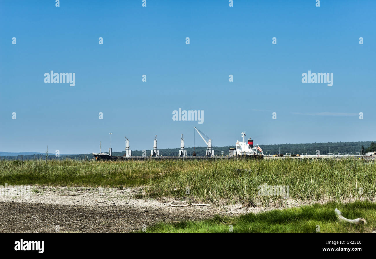 Una nave da carico in un porto commerciale la distanza da Sears isola a Searsport Maine in estate. Foto Stock