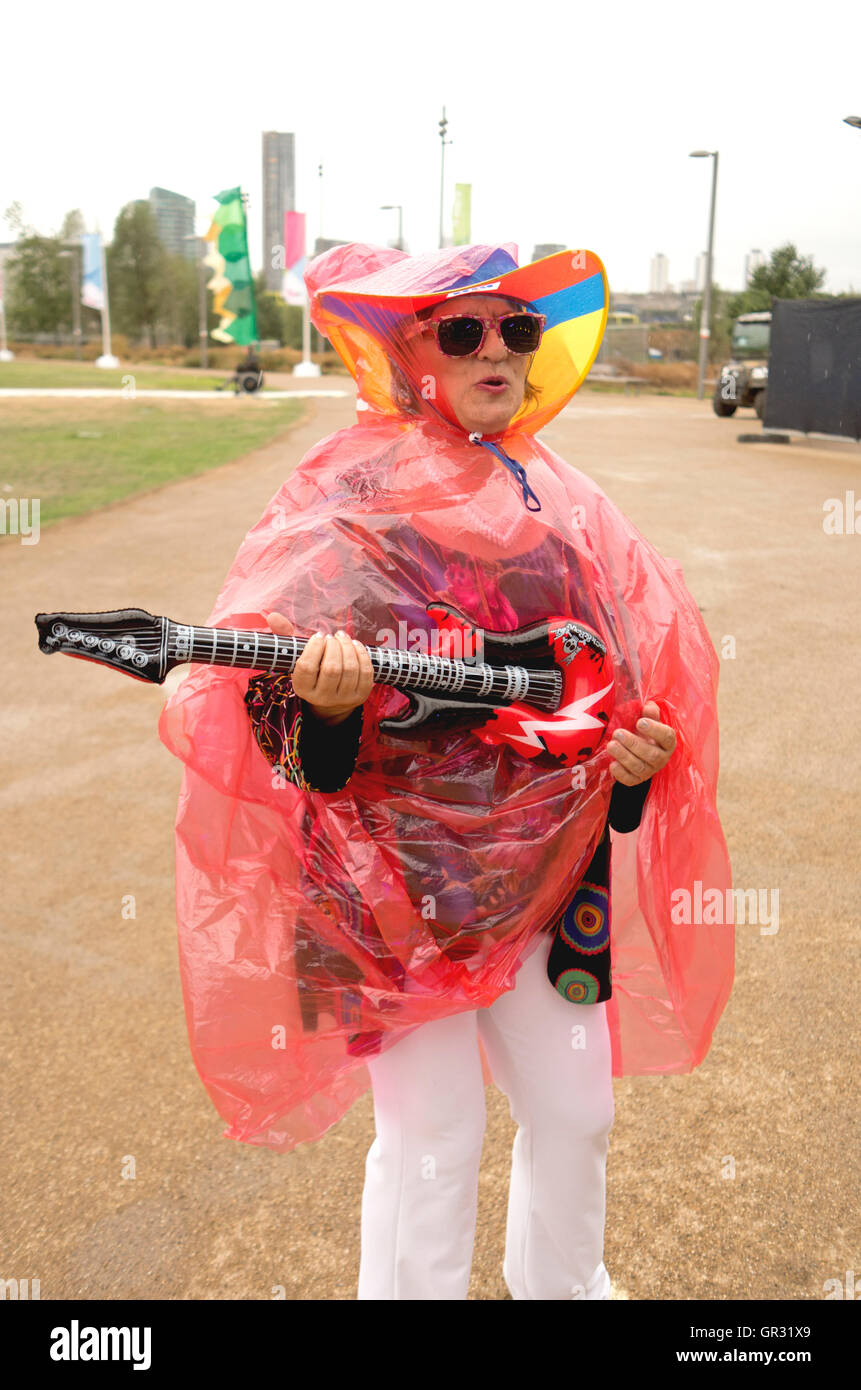 Amante della musica in una rosa poncho pioggia con una chitarra gonfiabile Foto Stock