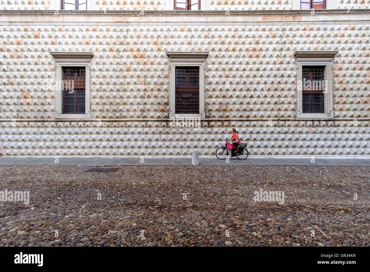 Ferrara, Italia - 21 agosto 2016. Donna in bicicletta di fronte al famoso Palazzo dei Diamanti. Foto Stock