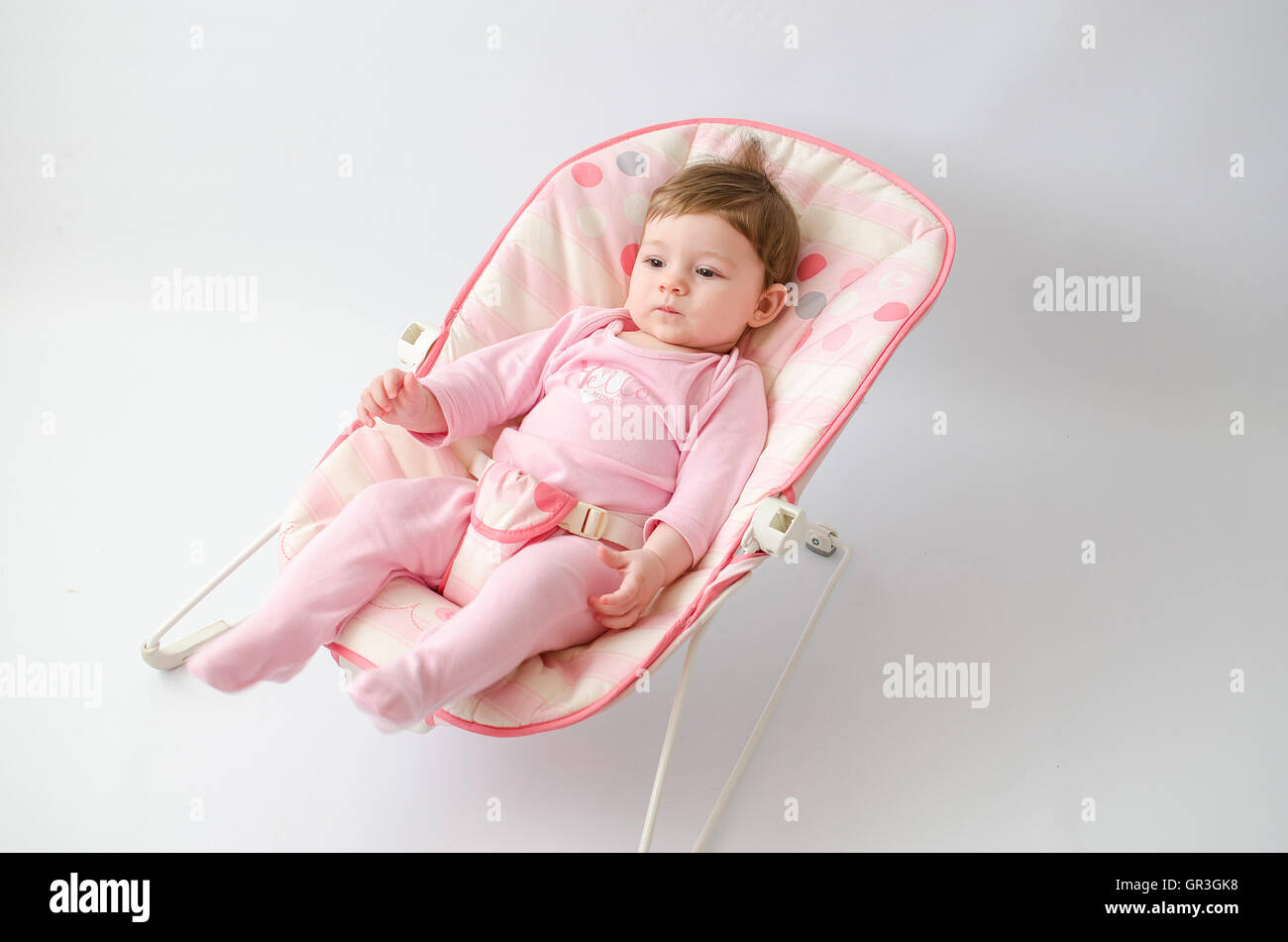 Bella Happy Baby girl in un buttafuori indossando onesie rosa Foto Stock