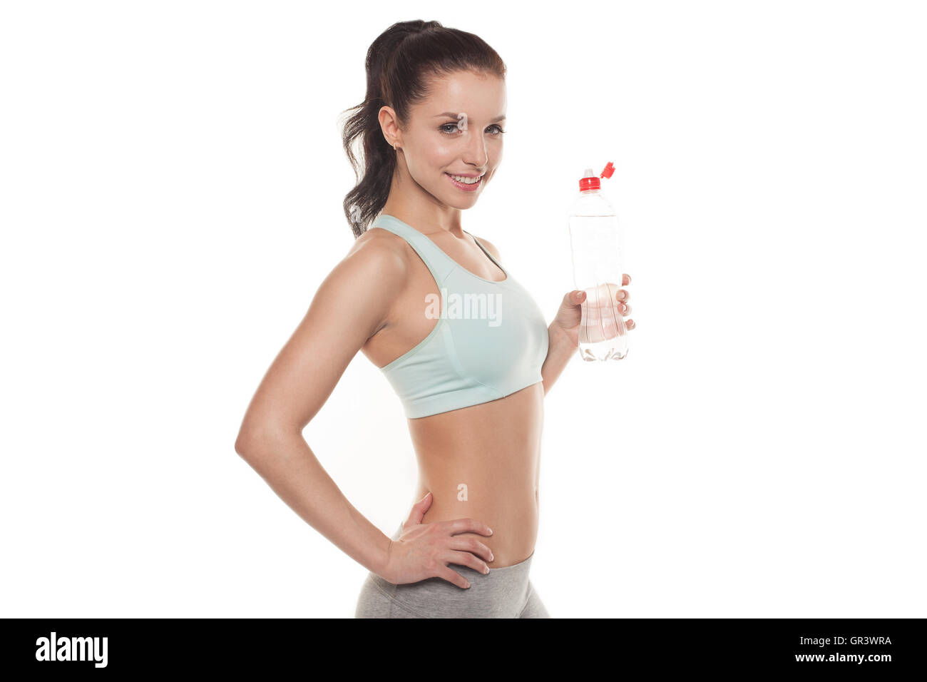 Ragazza sportiva acqua potabile da una bottiglia dopo una sessione di allenamento fitness training, isolato su sfondo bianco Foto Stock