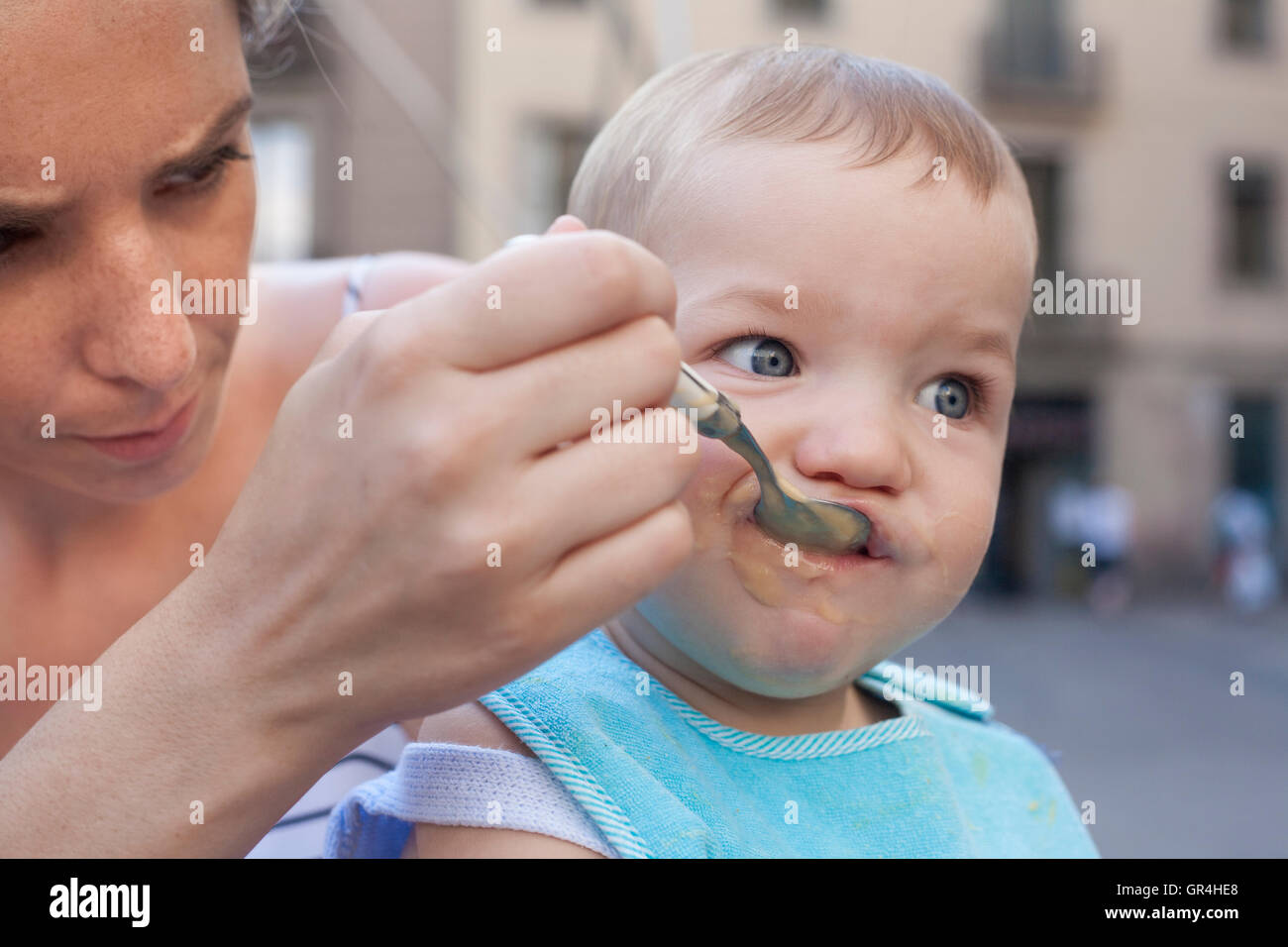 Madre che nutre il suo bambino Ragazzo con frutta poltiglia all'aperto Foto Stock