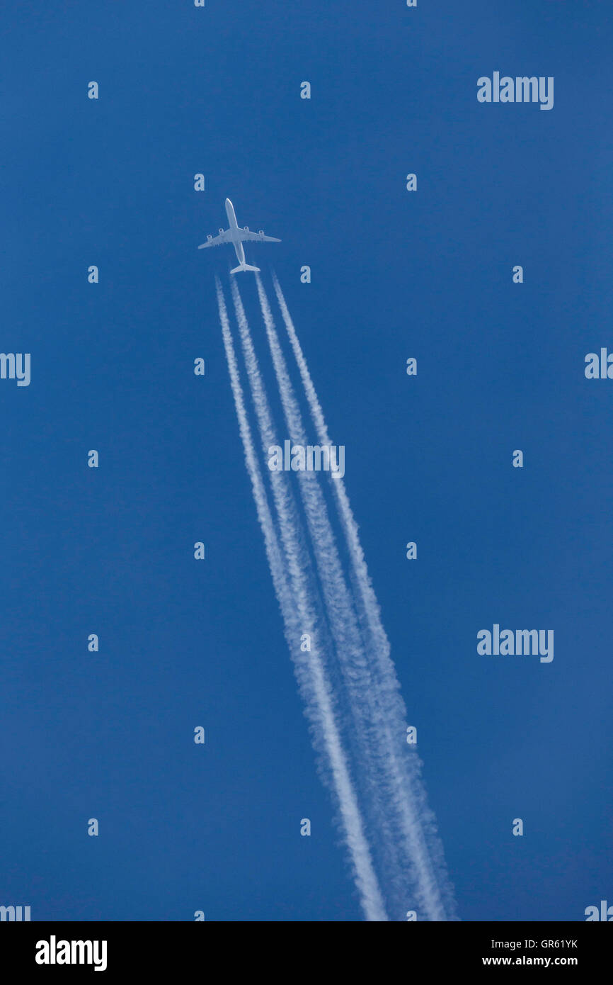 Airbus A340 aereo di linea volando ad altitudine di crociera con una spessa contrail dietro il velivolo Foto Stock