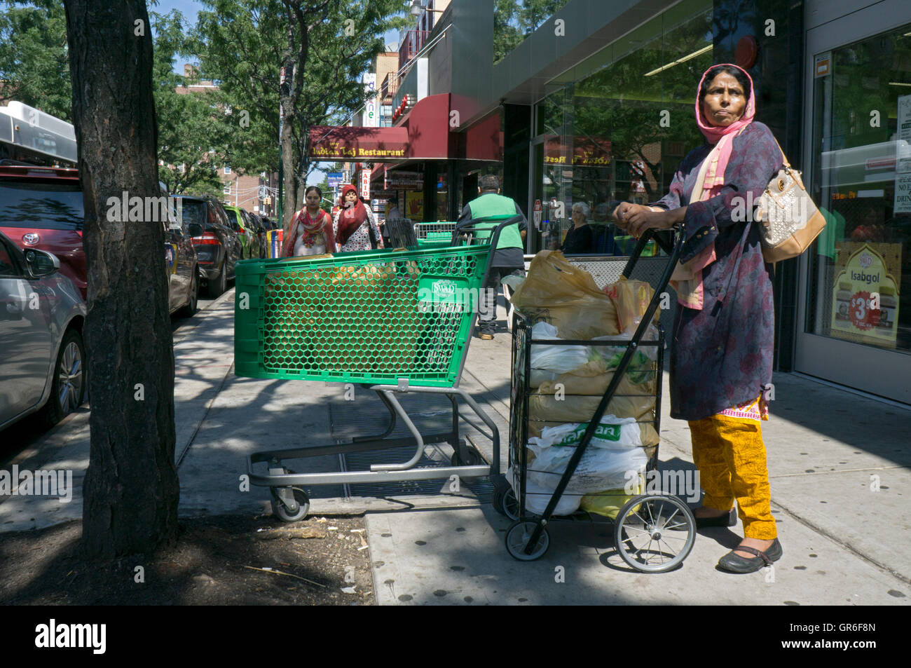 Una donna indiana al di fuori Patell fratelli supermercato sulla 74a Strada di Jackson Heights, Queens, a New York City. Foto Stock