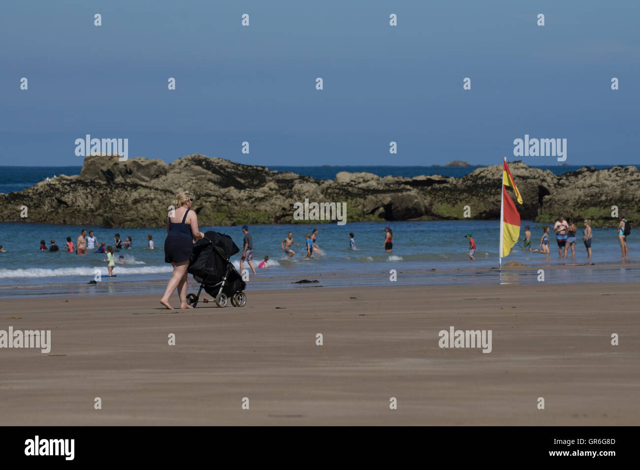 Donna spingendo una carrozzina lungo la spiaggia Plemont,Jersey,Isole del Canale Foto Stock