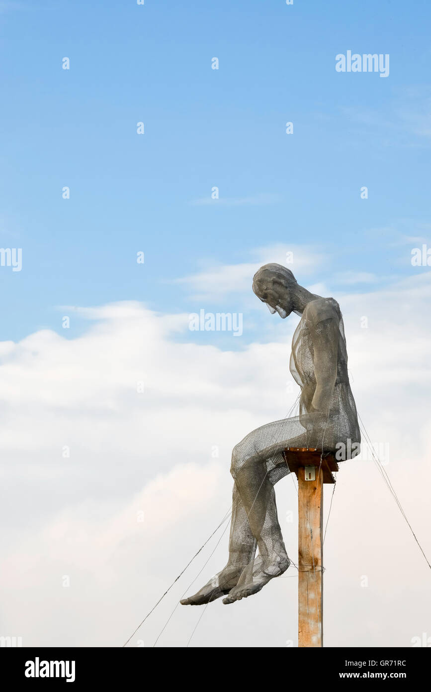 Ponendo l'uomo seduto tra le nuvole, cielo blu giorno Foto Stock