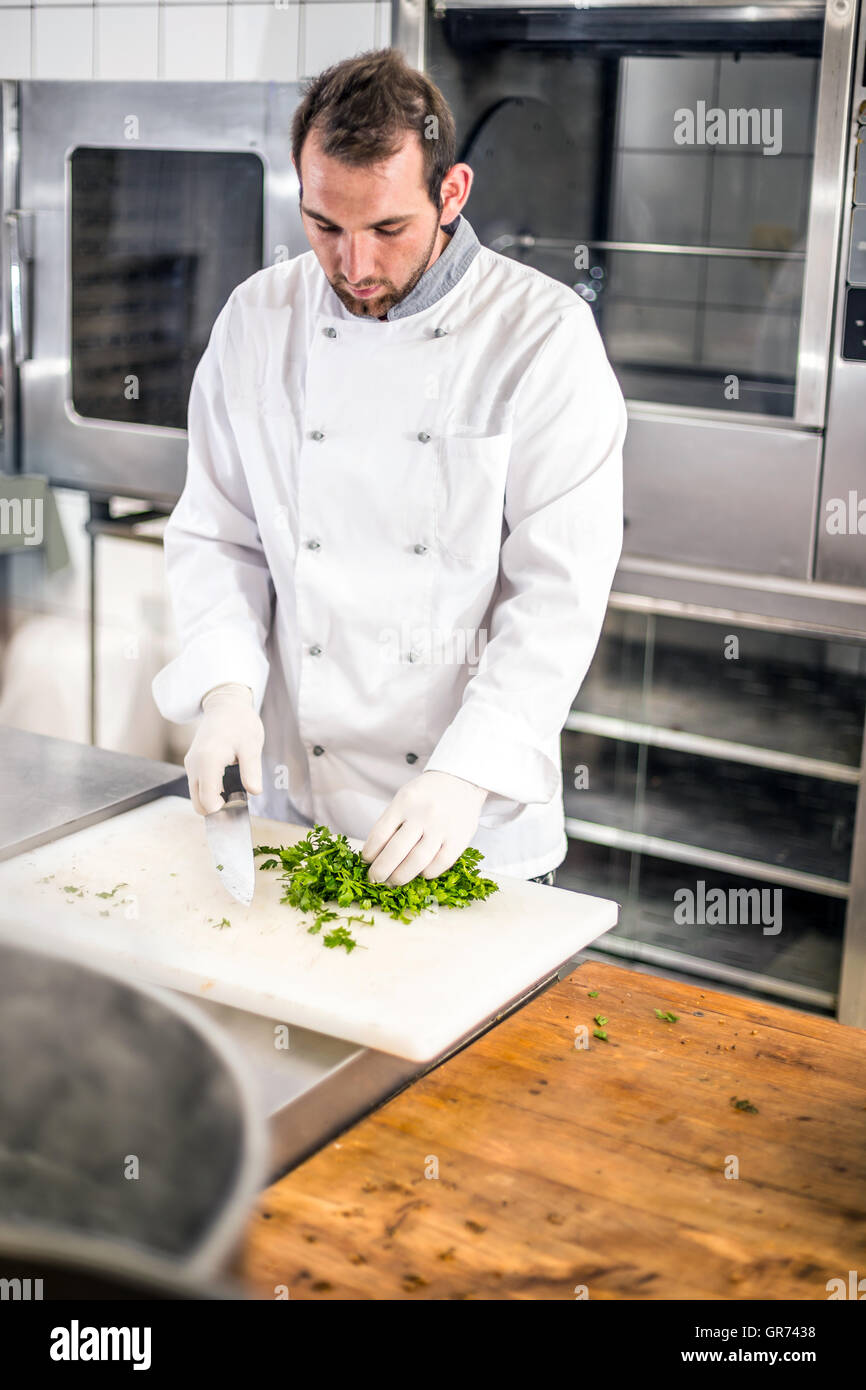 Lo chef maschio di prezzemolo tritato sul bordo di taglio Foto Stock