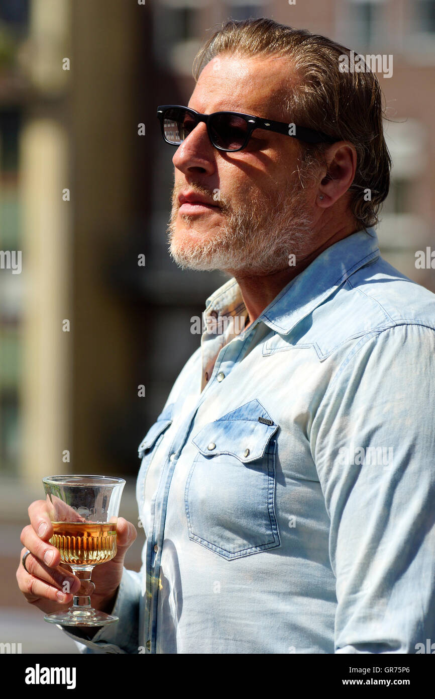 Uomo con una camicia in denim di bere alcol Foto Stock