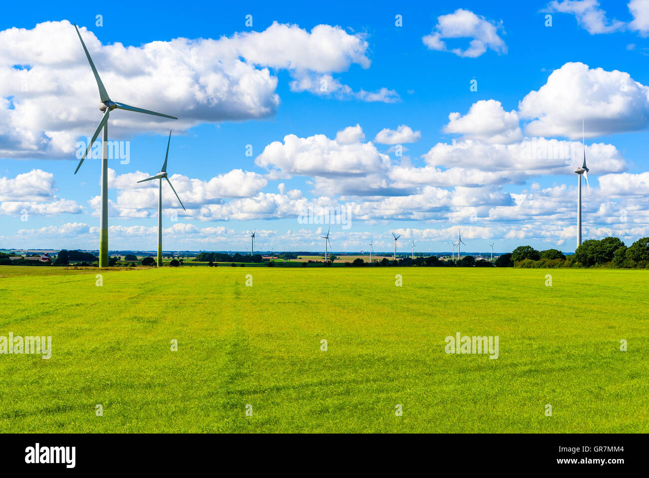 Energia sostenibile da turbine eoliche in terreni agricoli piana con nubi fini overhead. Skane nella Svezia meridionale. Foto Stock