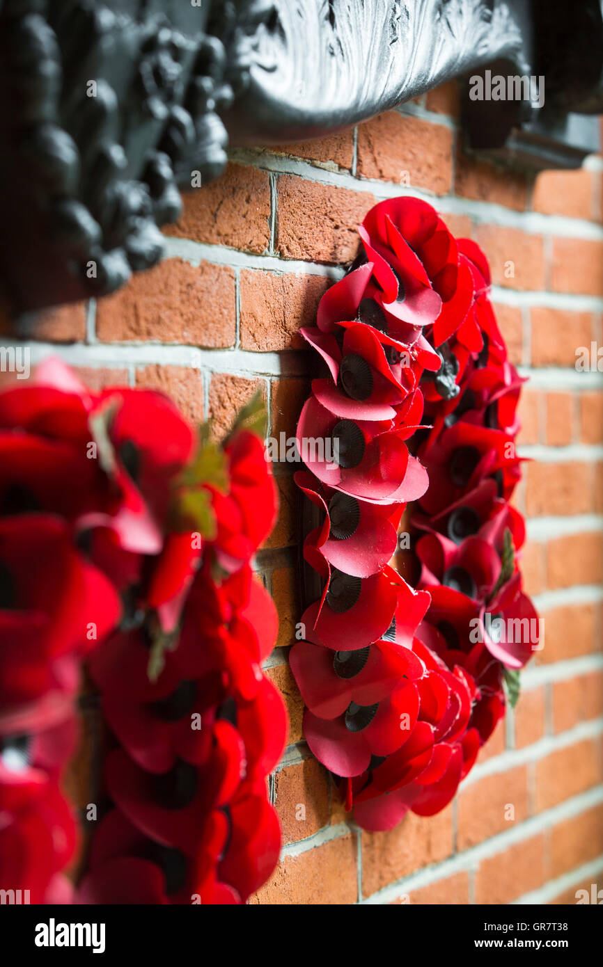 Un memorial wall con semi di papavero ghirlande adn palque con i nomi dei morti. Foto Stock